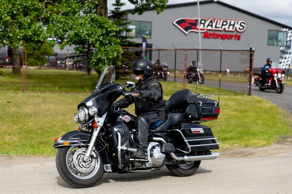 Black Harley-Davidson Ultra Classic motorcycle parked on gravel with Ralph's store sign visible in background.