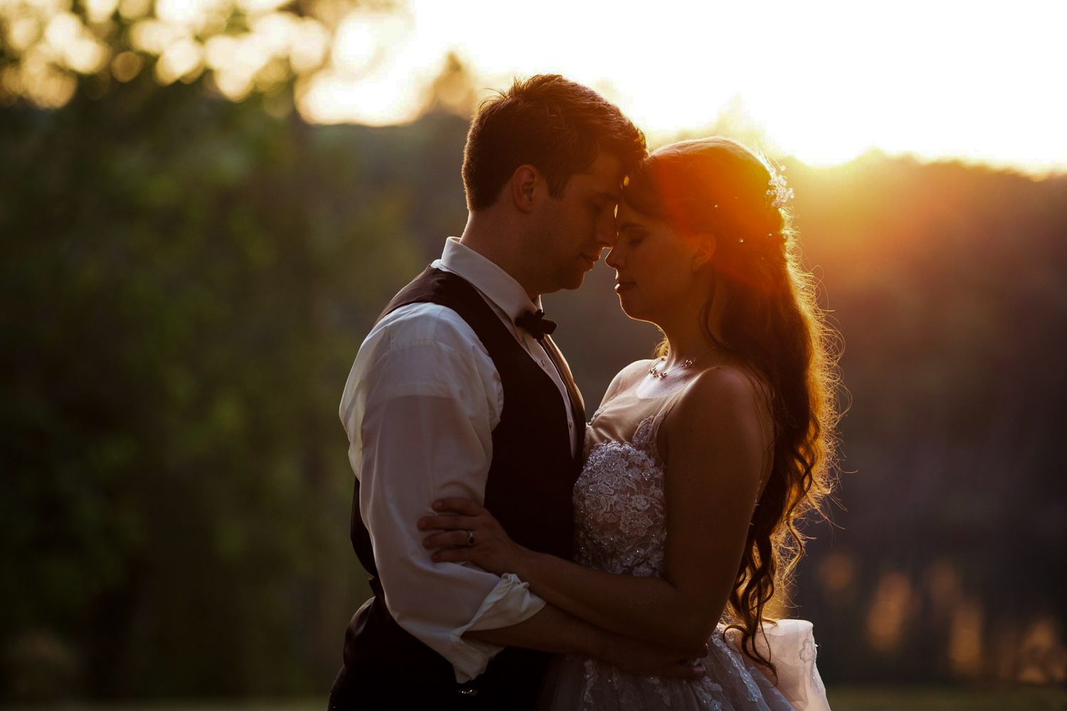 Romantic sunset silhouettes of a wedding couple embracing in golden light.