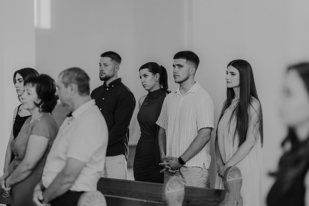 A group of wedding attendees standing in a row during a church ceremony.