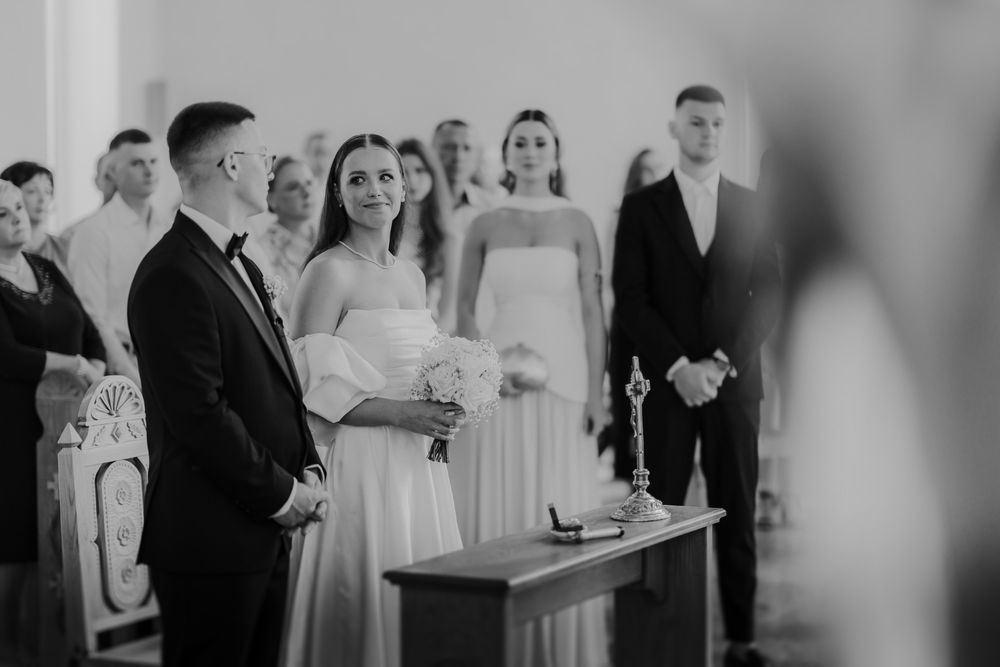 A black and white photo of a wedding ceremony in progress with guests observing in a church.