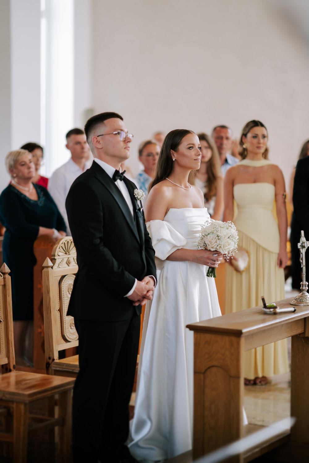 A couple stands at the altar during their wedding ceremony in an elegant church setting.