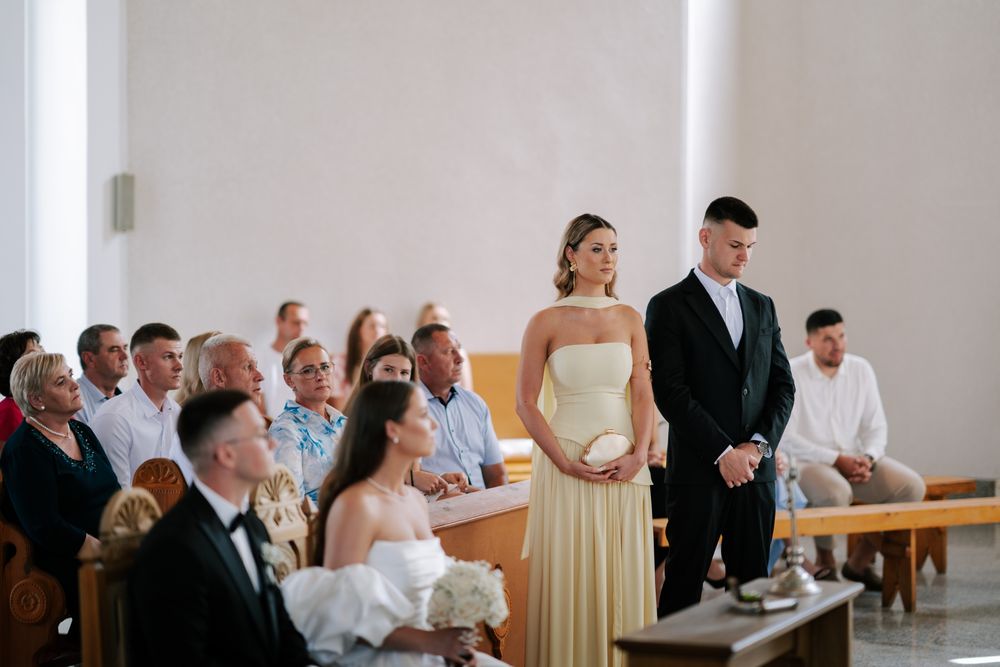 Wedding ceremony in progress with guests seated in church pews watching the couple at the altar.