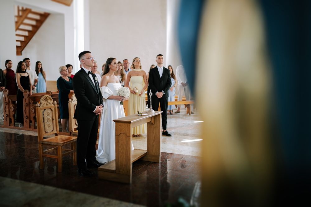 Wedding ceremony taking place in a traditional church sanctuary with wooden pews and natural light.