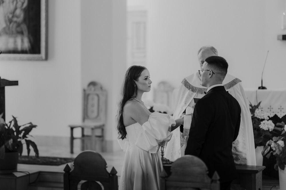 Black and white image of wedding guests seated in church pews during ceremony.