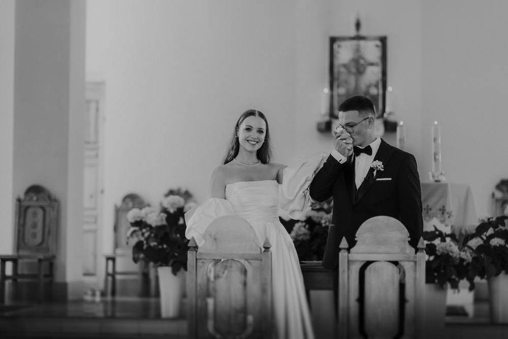 Black and white church ceremony with elegant floral decorations.