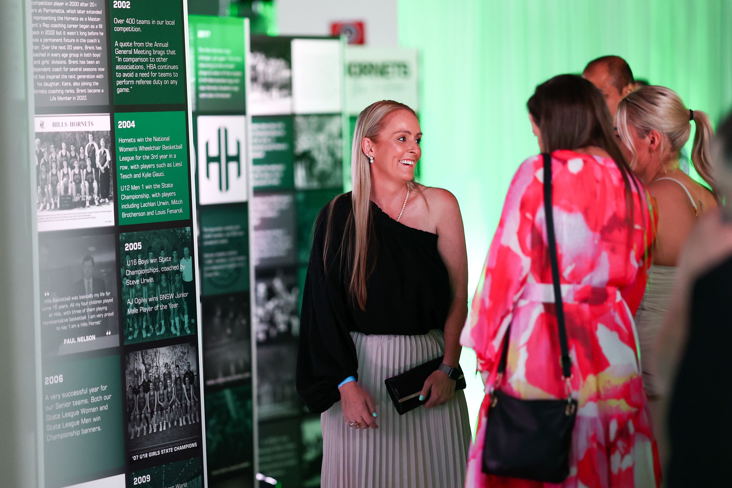 Exhibition space with green lighting and informational panels displayed on walls.
