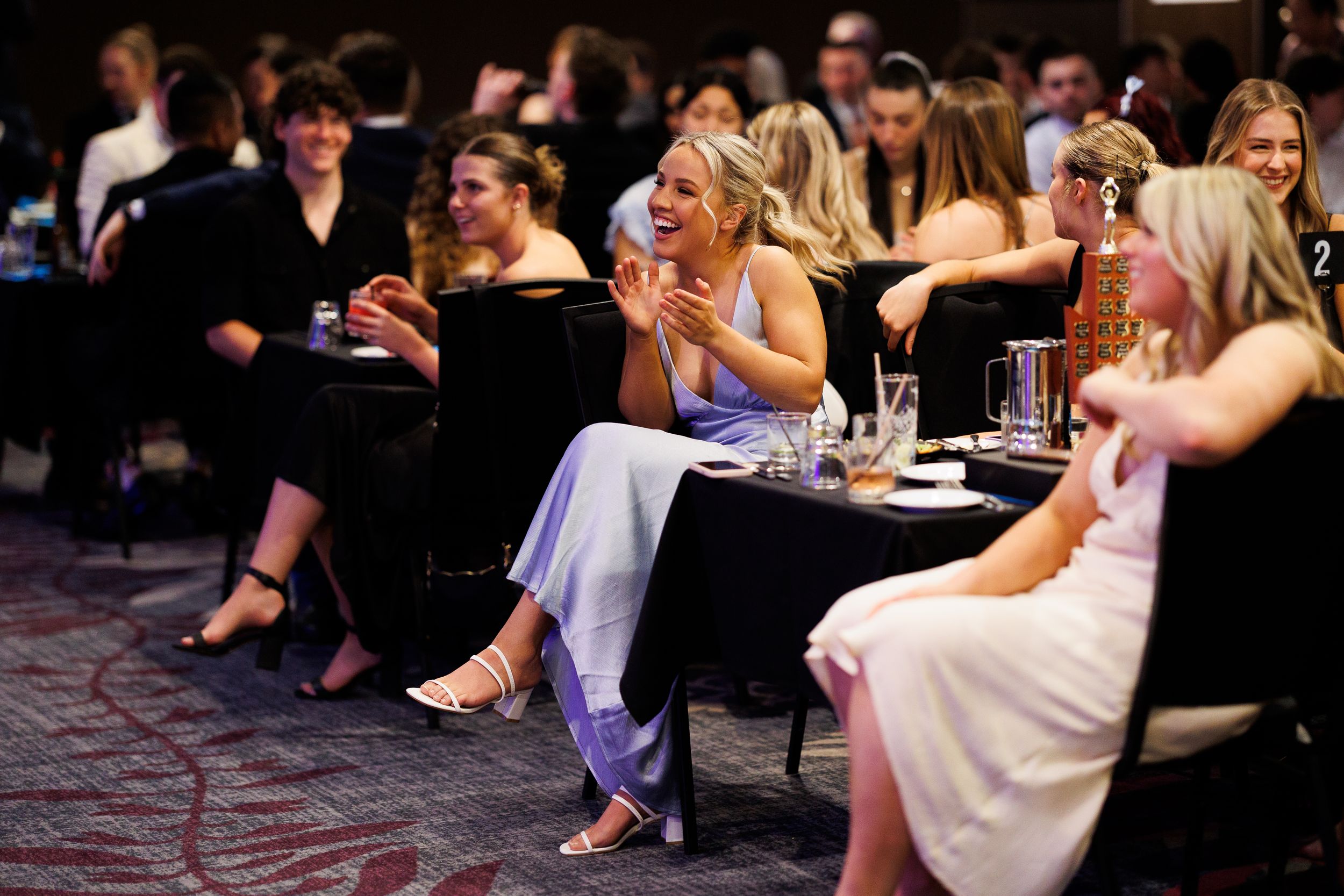 People seated at tables during an indoor social gathering or event.