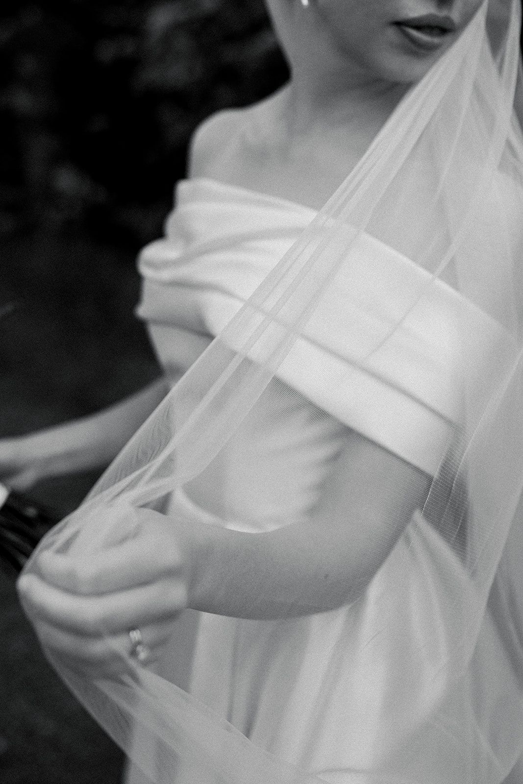 Close-up black and white photos of a wedding dress with delicate tulle fabric and elegant draping details.