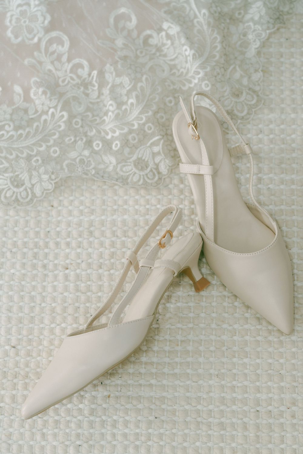 White slingback pointed toe kitten heel shoes with delicate strap details shown from multiple angles on lace background.