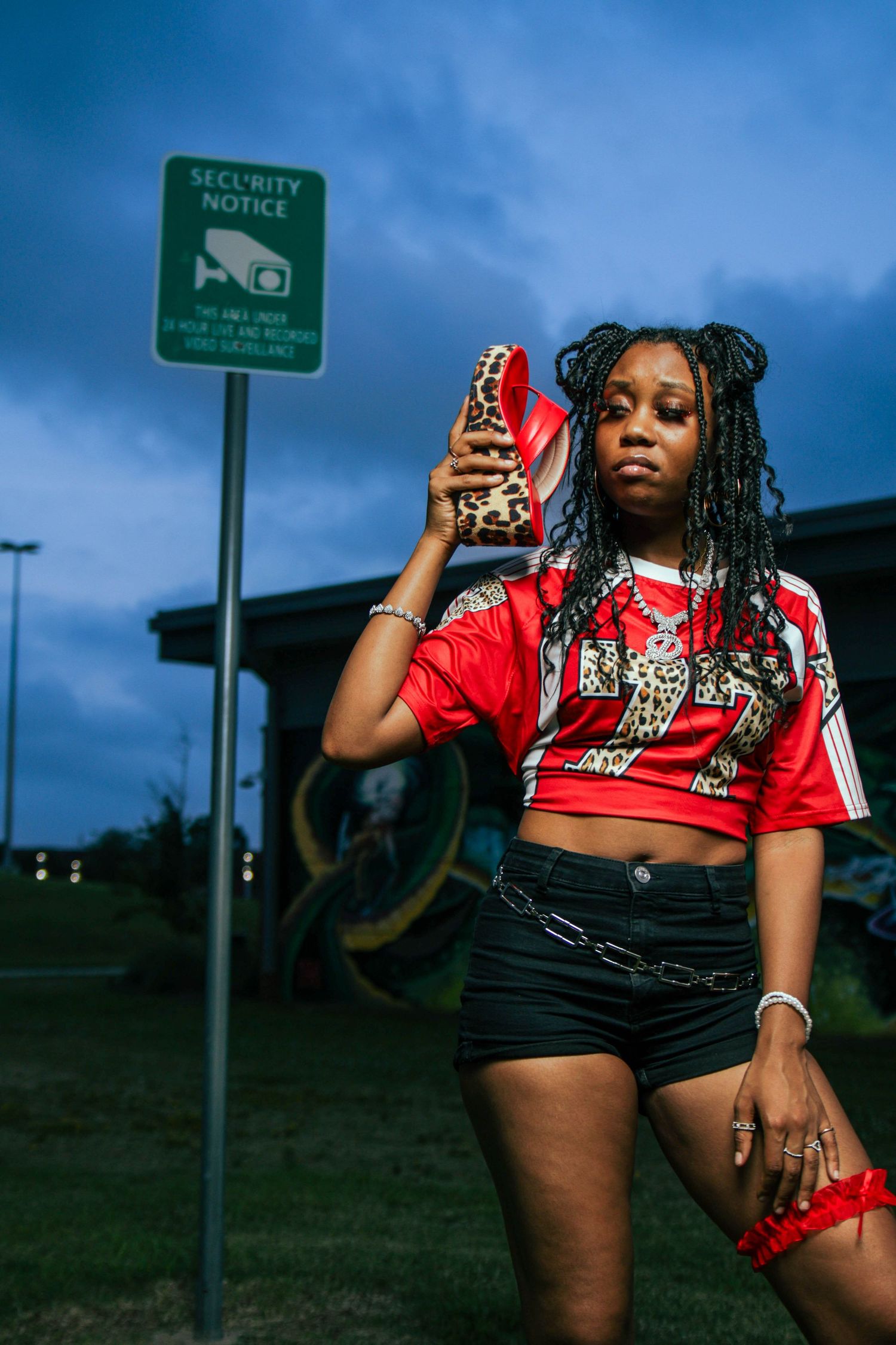 Outdoor photoshoot featuring red graphic t-shirt and shorts against evening sky.
