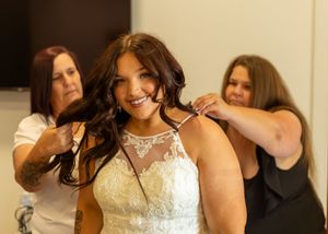 Two assistants help a bride with her hair while getting ready in a beautiful lace wedding gown. Lousiana Wedding. Texas Wedding. bridal