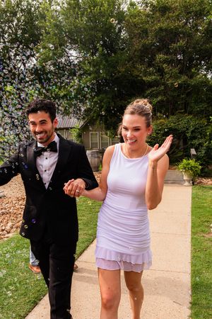 Smiling couple exit after wedding, surrounded by bubbles. The Little Wren Rockwall, TX. DFW wedding. Dallas Fort Worth Wedding. bride/groom