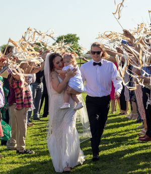 Newlyweds exit their wedding ceremony under a shower of ribbons held by guests. Fort Worth, Texas