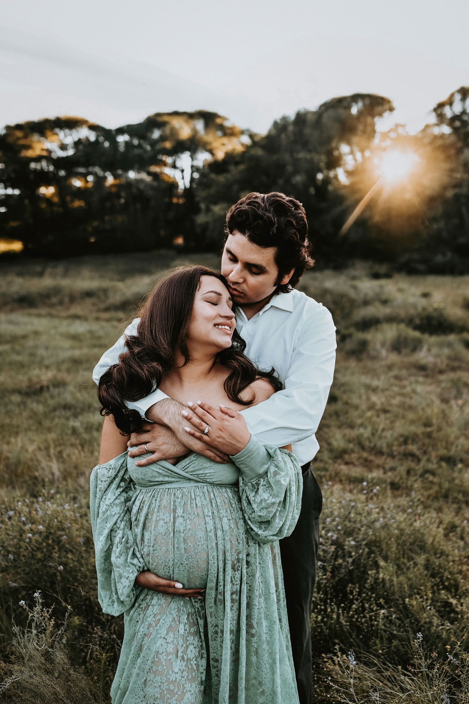 mother and father embrace as  they pose for their maternity photos at sunset by april pinto photography captured on lake grapevine