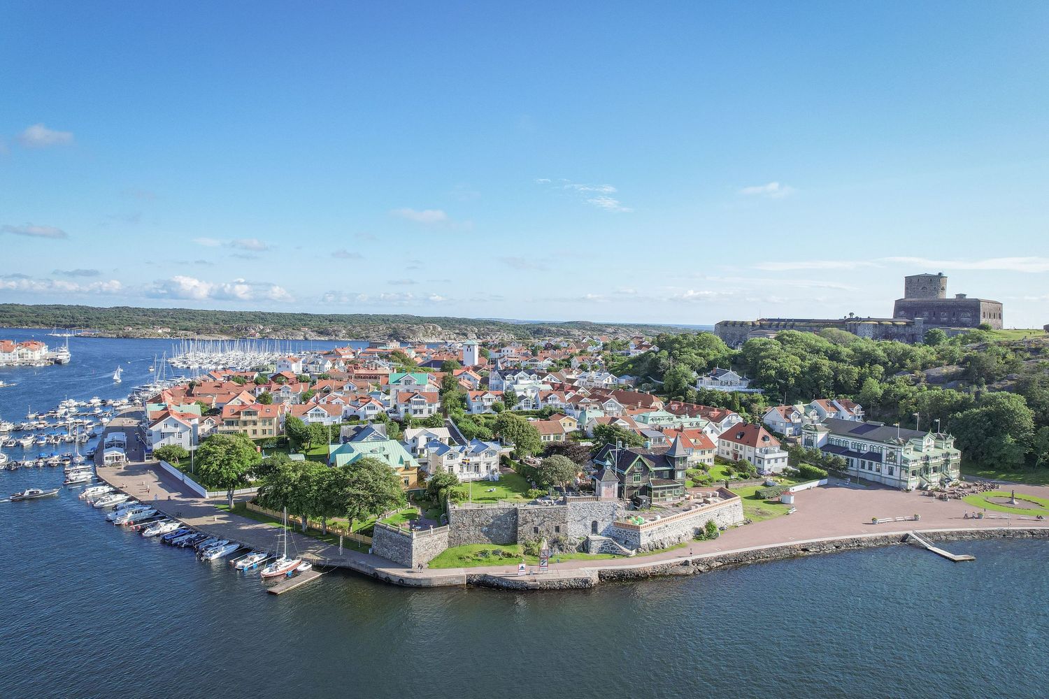 Aerial view of coastal town in Whitby showing historic harbor, colorful buildings and Whitby Abbey on hilltop.