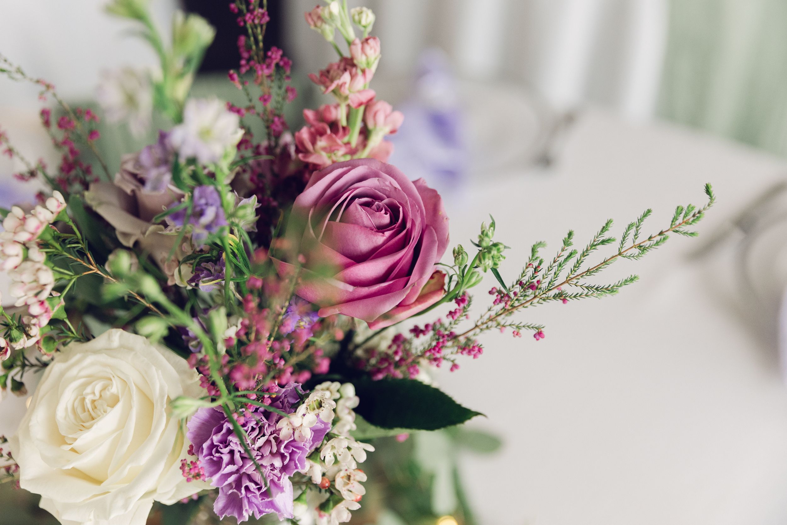 Close-up of an elegant floral arrangement with purple and white roses.