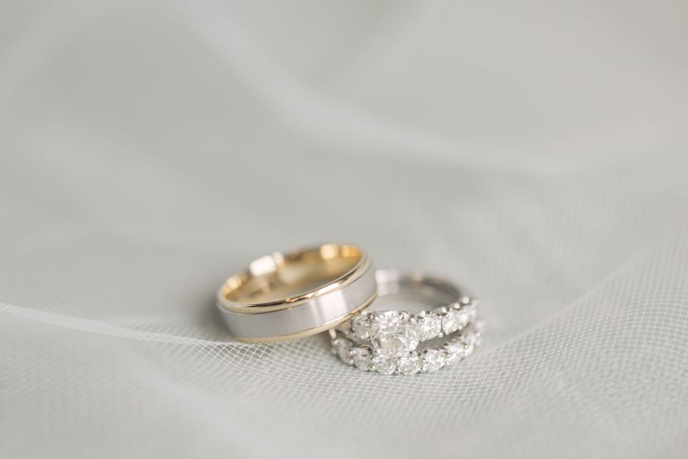 Close-up of elegant diamond engagement ring and wedding band on textured fabric.