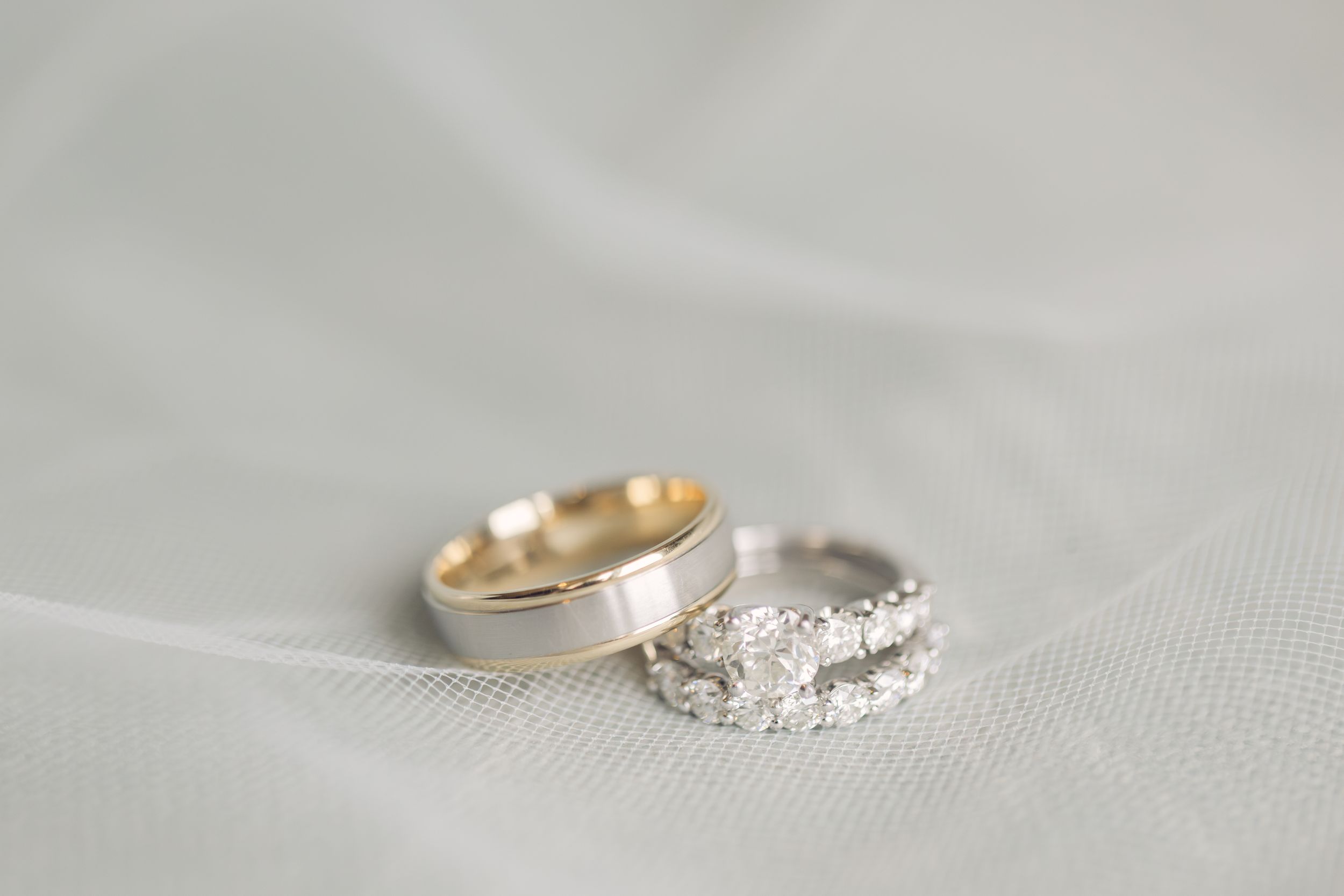 Close-up of elegant diamond engagement ring and wedding band on textured fabric.