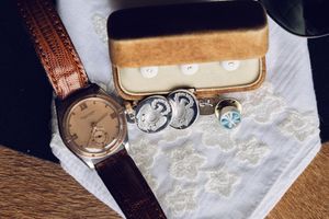 Three vintage leather watch boxes displayed on a wooden surface.