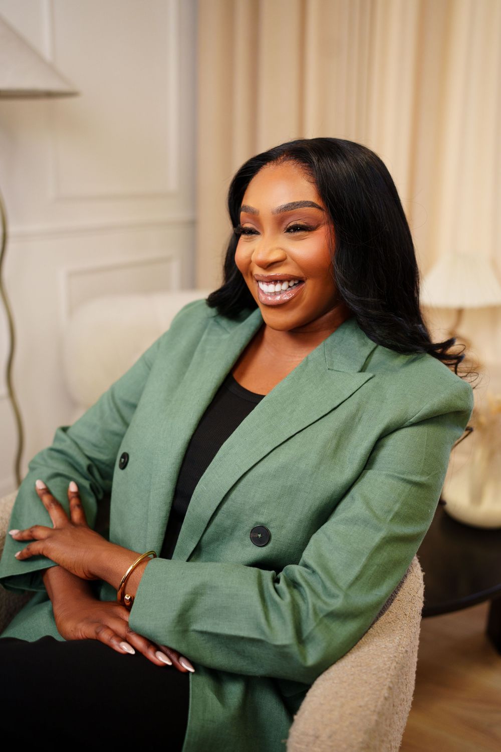 Woman in green blazer and black top poses confidently in professional indoor setting.