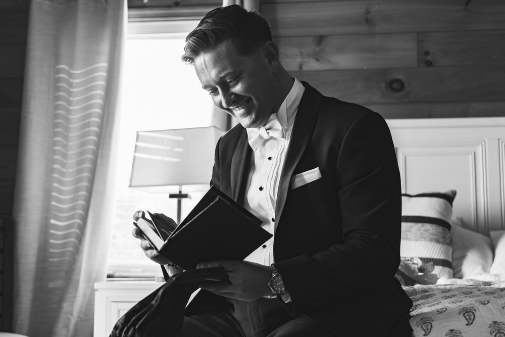 A person in a tuxedo sits reading a book in black and white vintage photography.