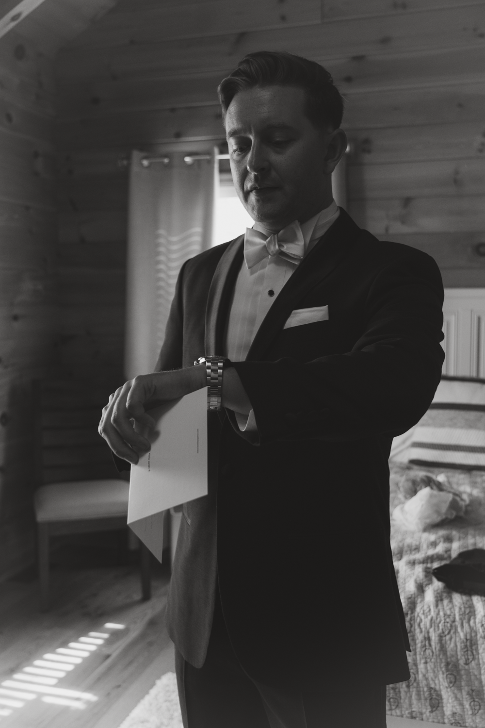 An elegant monochrome image of someone checking their watch while wearing a tuxedo.