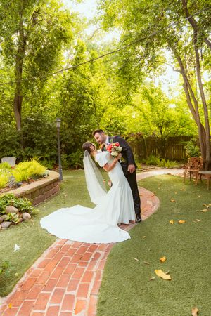 A series of romantic spins between two people in wedding attire on a brick path surrounded by lush greenery.