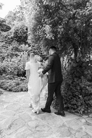 A black and white series of intimate wedding portraits on a stone path surrounded by foliage.