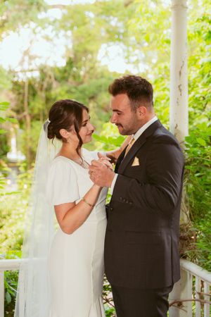 Couple shares an intimate moment during their wedding on a white porch surrounded by greenery.