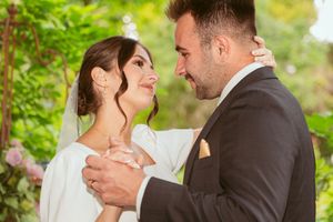 A newlywed couple shares an intimate moment during their wedding celebration in a garden setting.