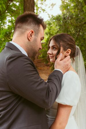 A tender moment between newlyweds as they share an intimate outdoor portrait in a garden setting.