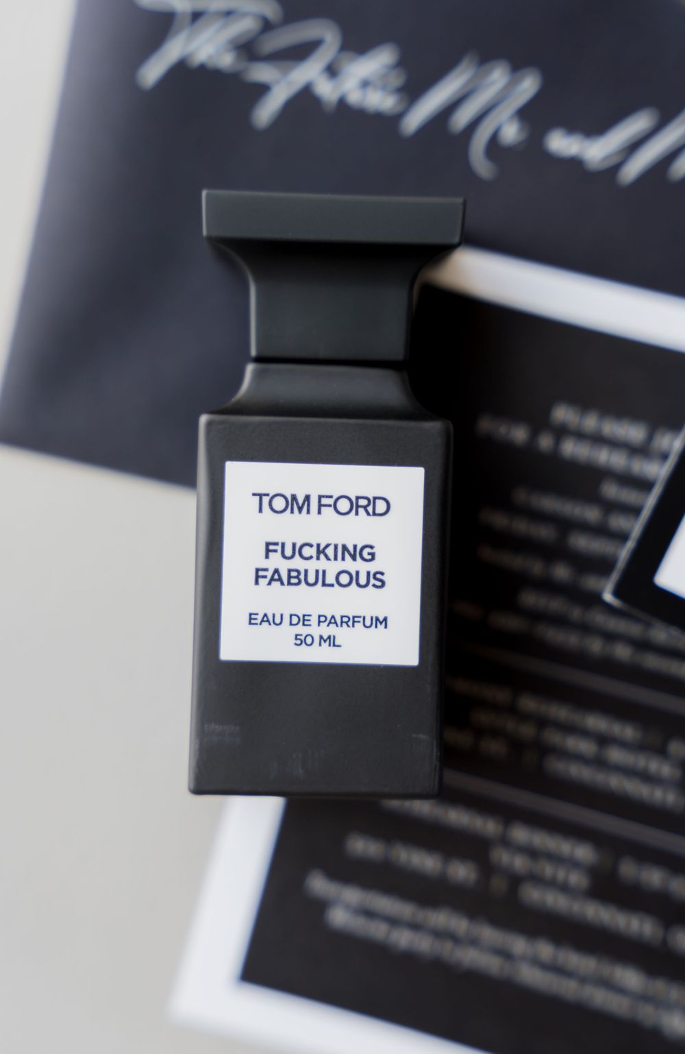 Luxury black Tom Ford perfume bottle with provocative name against dark background.