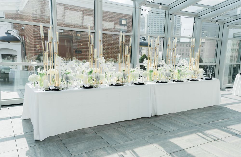 Elegant indoor wedding venue with glass ceilings and white floral arrangements lining the bright, open space.