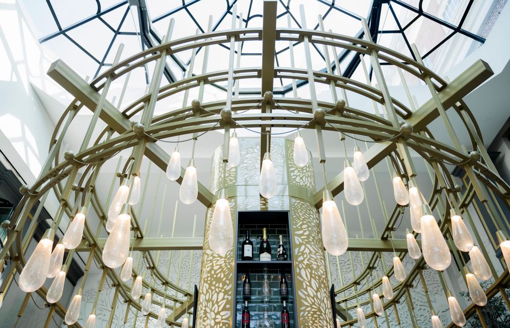 Modern circular chandelier with geometric design and hanging glass pendants illuminates an elegant interior space.