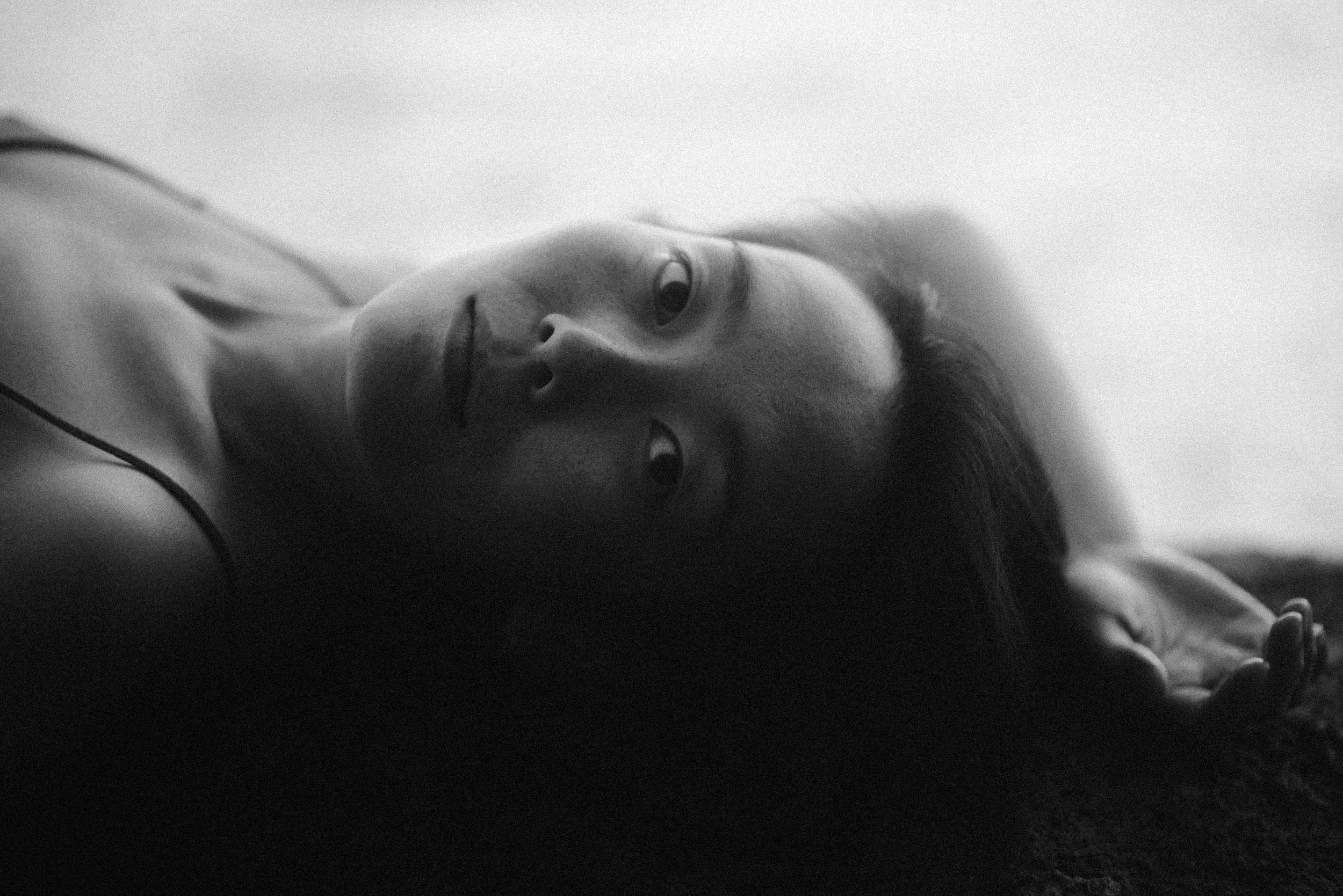Black and white artistic portrait of a person in shadow lying down.