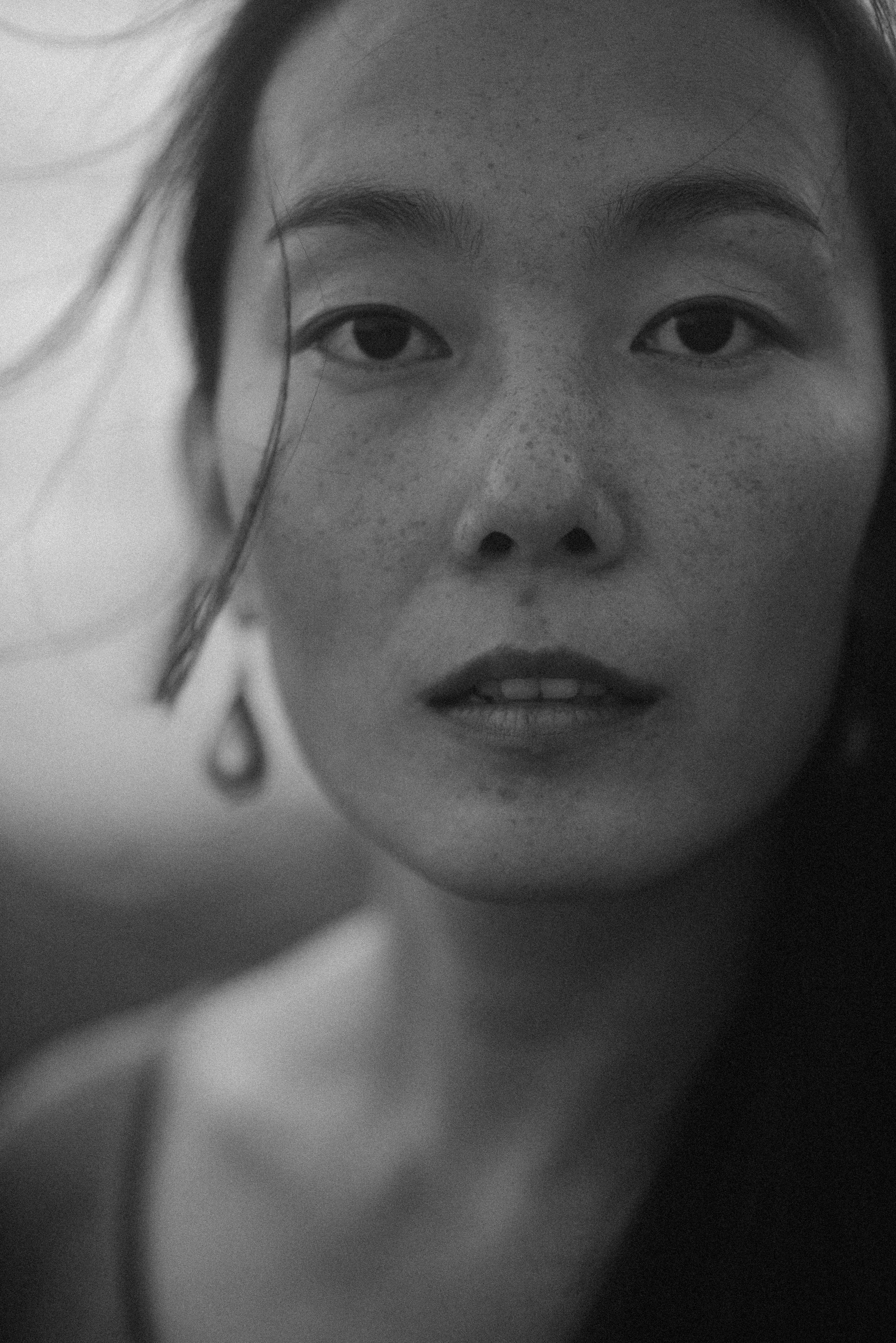 Close-up black and white portrait displaying serene expression with wind-swept hair.