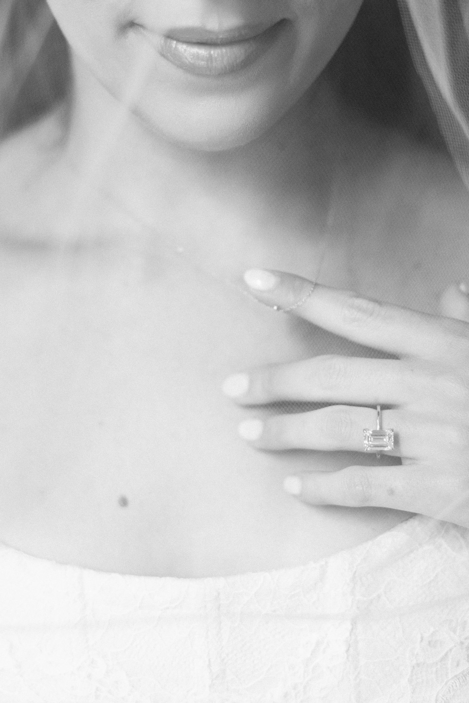 Close-up black and white shot showcasing an elegant engagement ring on a bride's delicate hand.