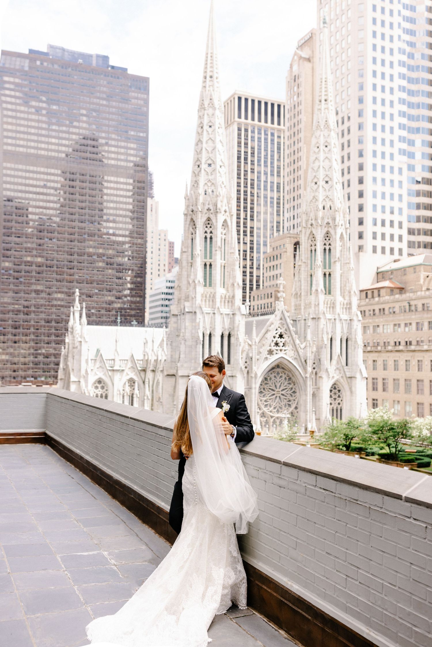 A bridal couple on a rooftop with St. Patrick's Cathedral and New York City skyline in the background.