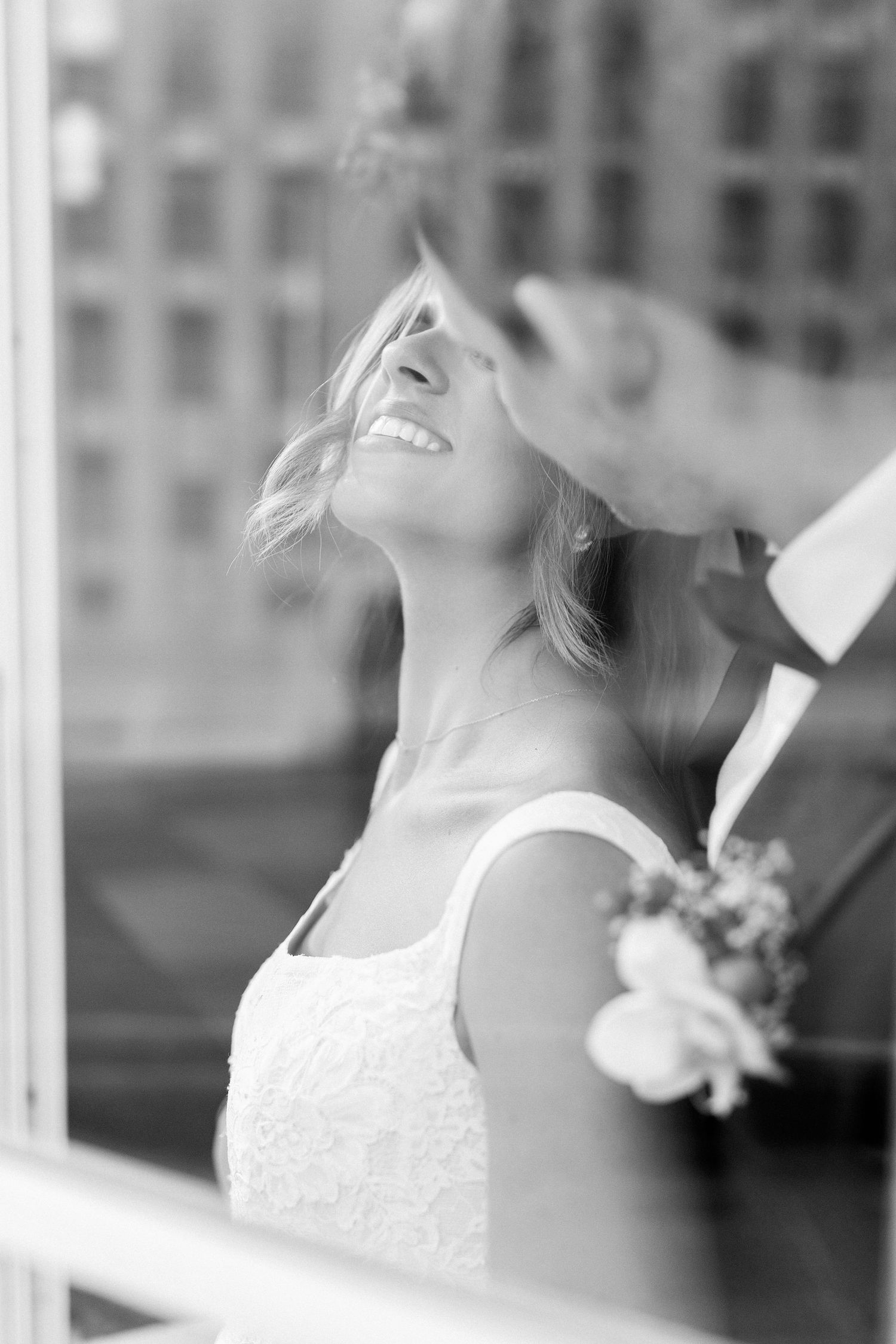 Black and white portrait of a joyful bride looking up with a genuine smile.