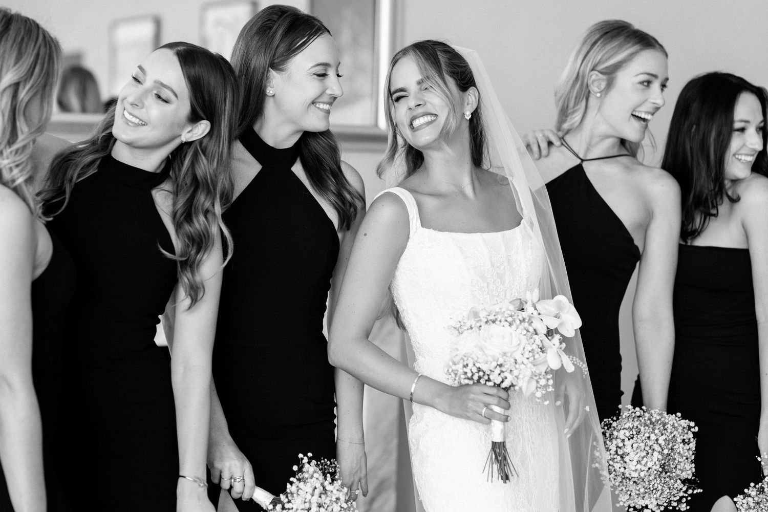 Wedding party in contrasting black and white attire smiling together during formal photos.