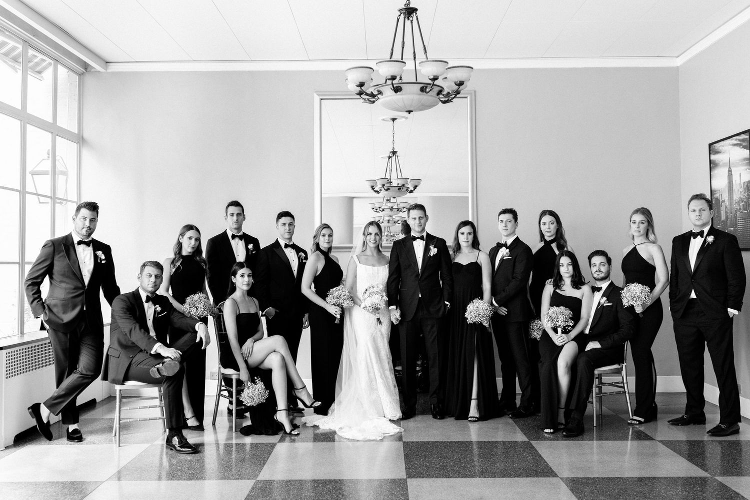 Elegant black and white wedding party portrait in luxurious venue with classic decor.