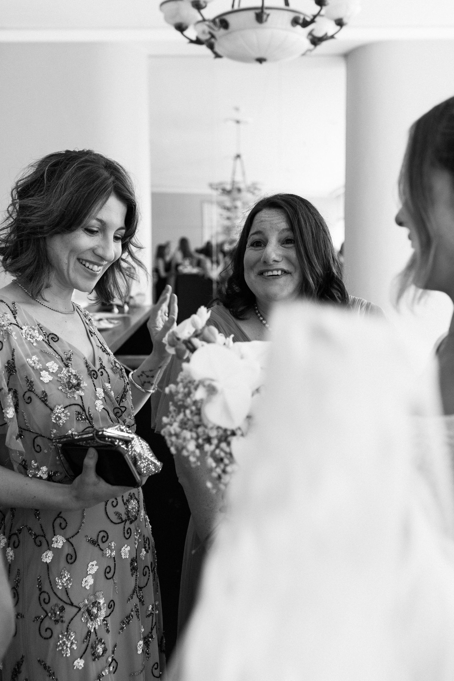 Wedding guests in floral dresses share a joyful moment during the celebration.