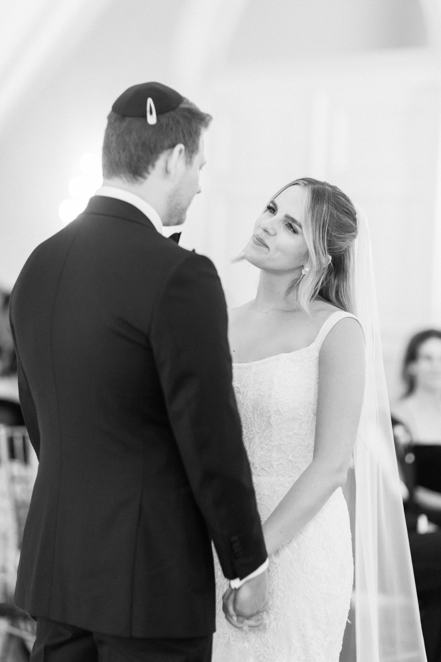 Black and white photo of couple during wedding ceremony exchanging vows at the altar.