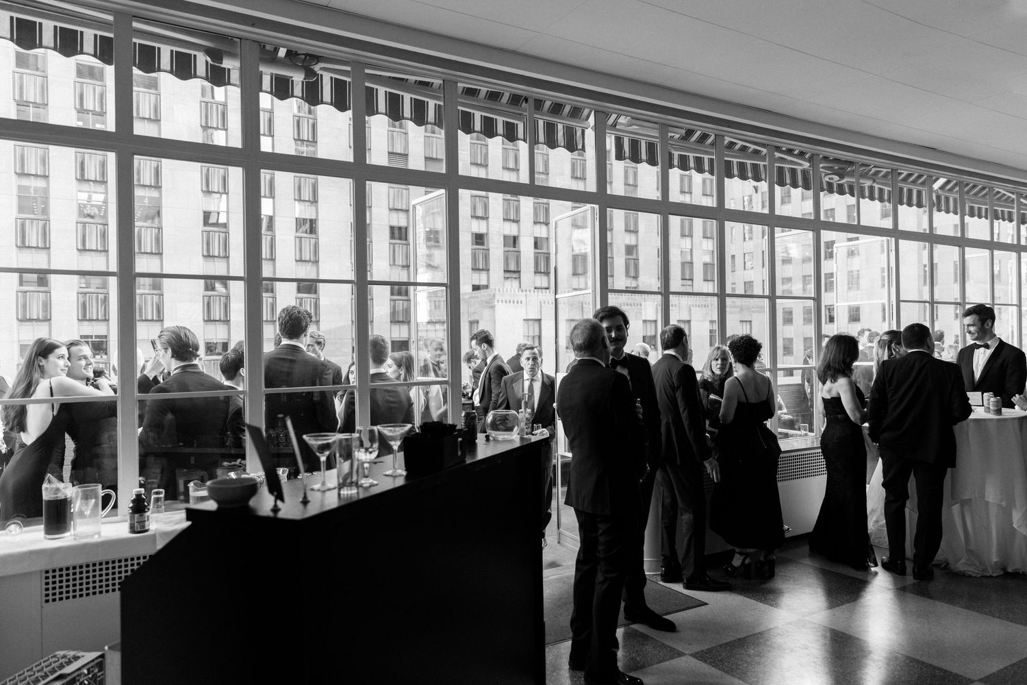 Elegant reception space with large windows and guests mingling at cocktail hour.