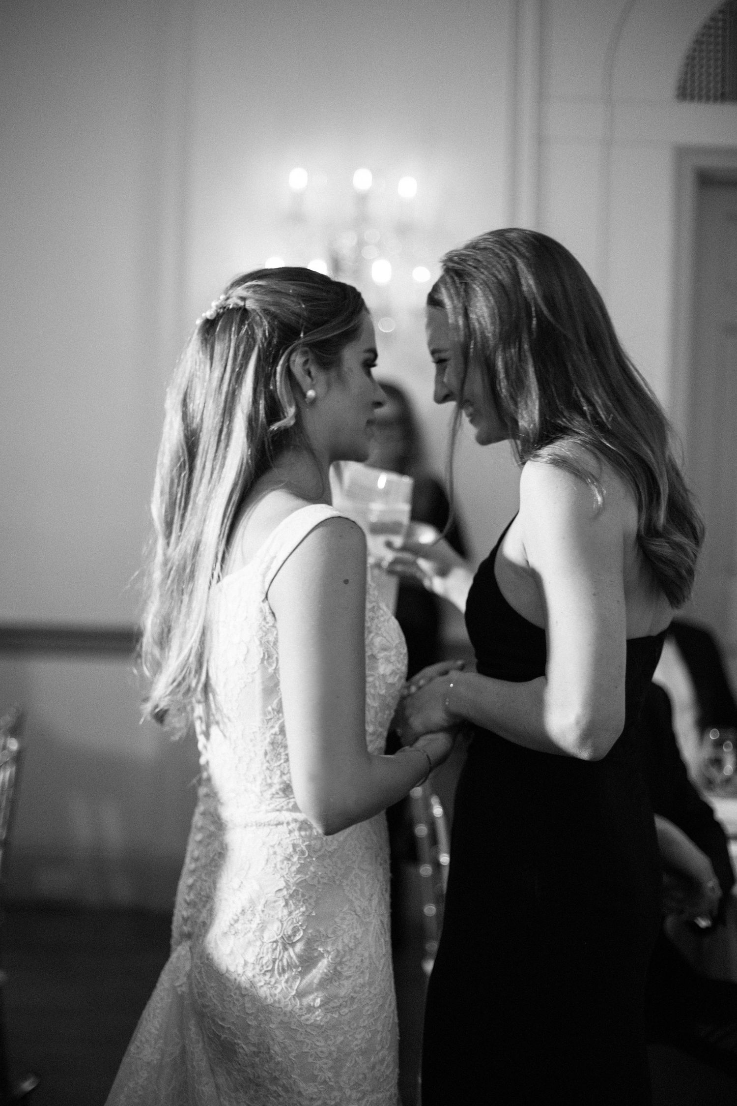 Intimate black and white candid moment between two guests at wedding reception.