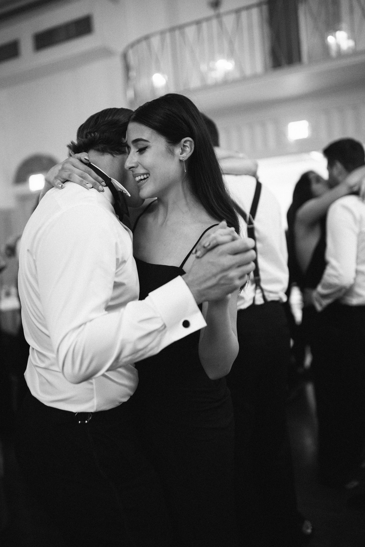 A black and white photo of a couple sharing an intimate slow dance moment at an elegant event.