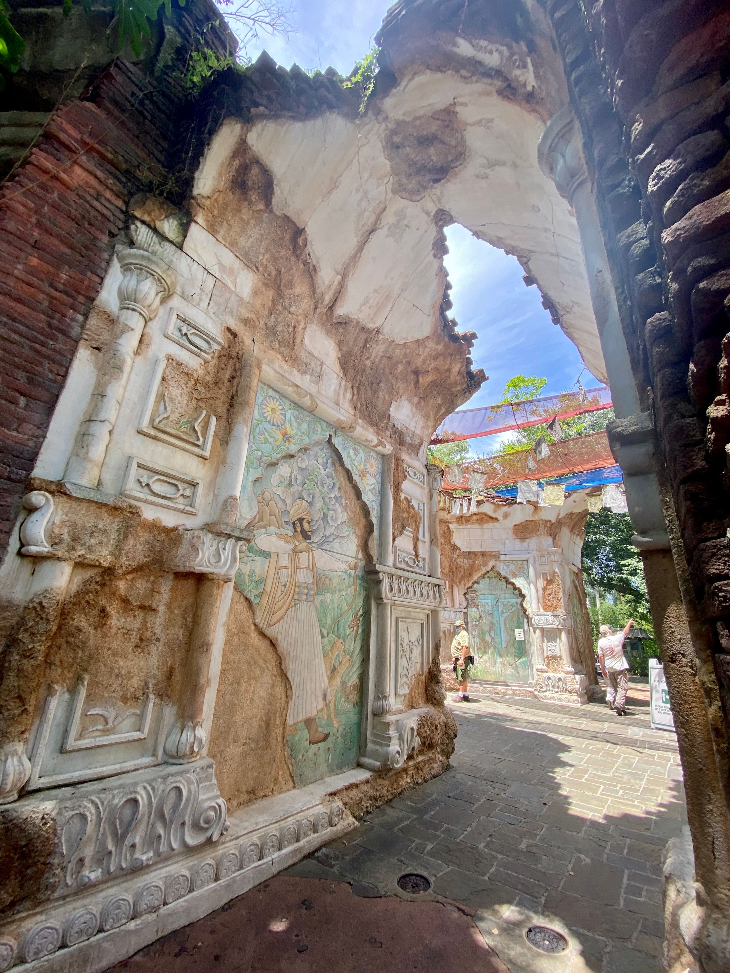 Stone archways and ornate carvings line a pathway through ancient ruins at a Buddhist temple in Asia.