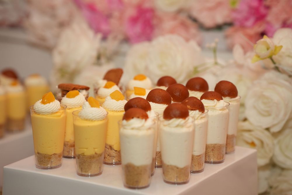 Elegant dessert cups with whipped cream, custard, and macarons displayed on a tiered stand at a wedding reception.