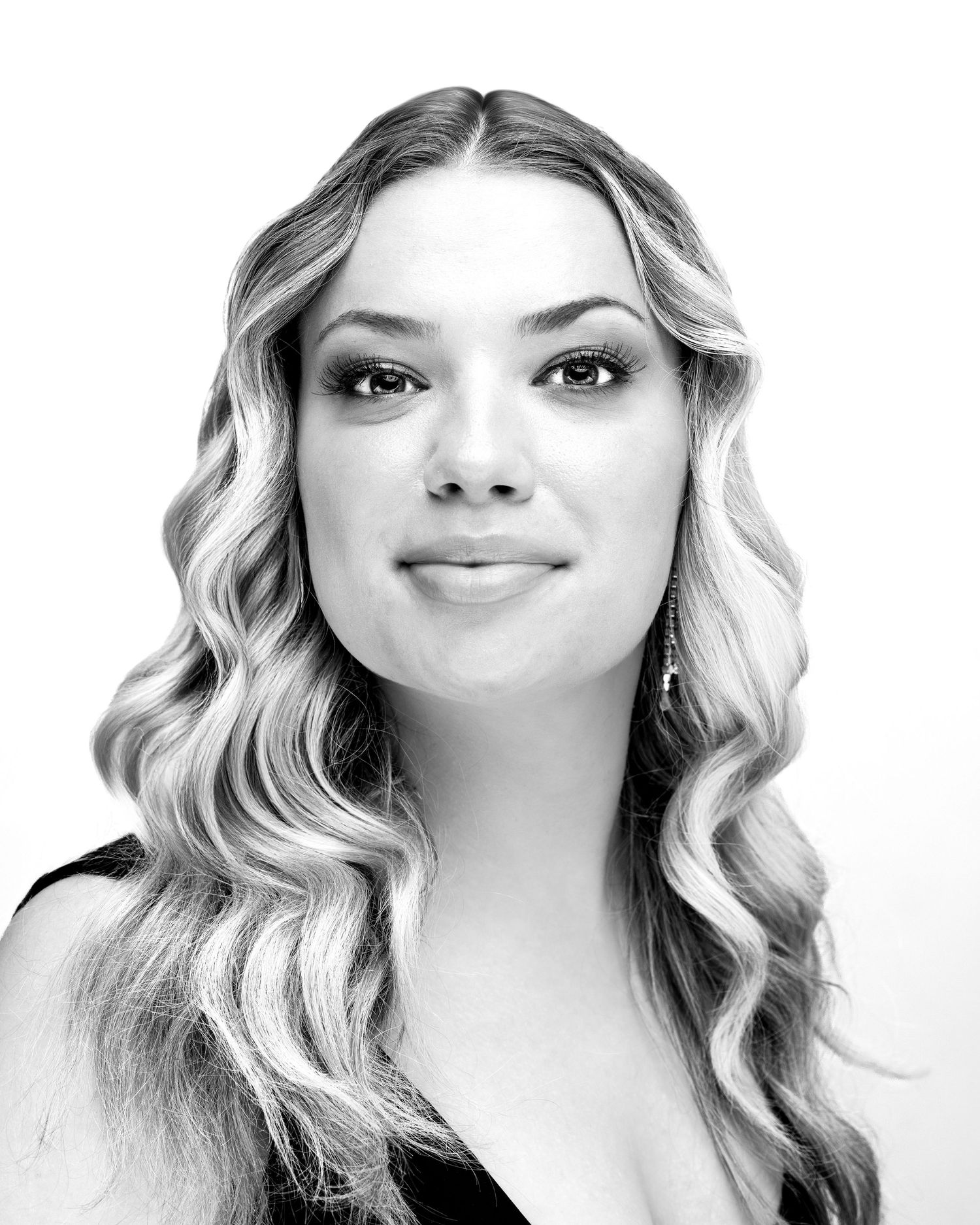 Beauty portrait with wavy blonde hair and soft pink makeup against blue background.
