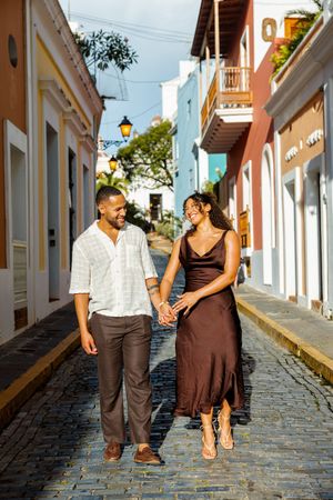Happy couple walking hand in hand on cobblestone streets of colorful Old San Juan.